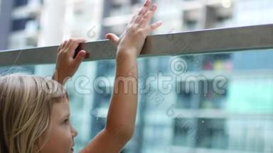 一个小女孩在玻璃栏杆上偷看。